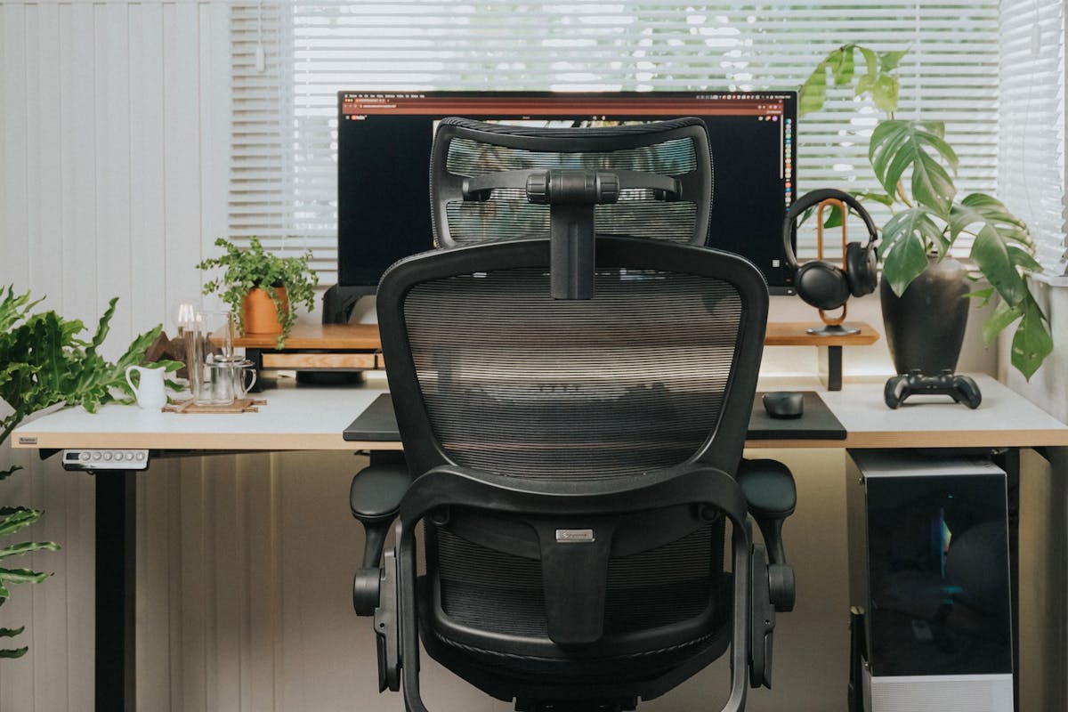 Modern home office with ergonomic mesh chair, desk, and greenery — ideal WFH setup
