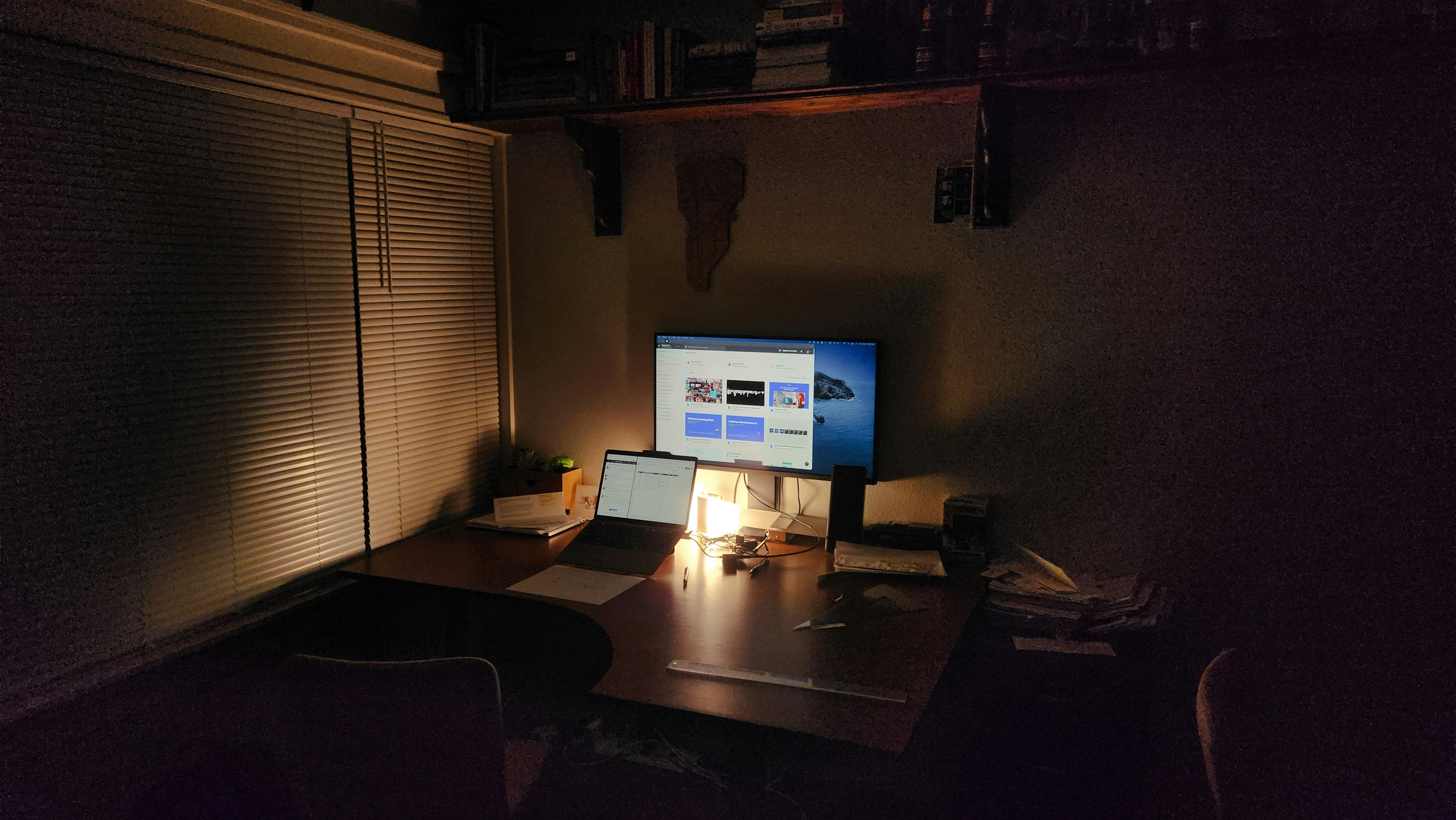 LED architect desk lamp casting warm task light across a dark home office workspace with mechanical keyboard