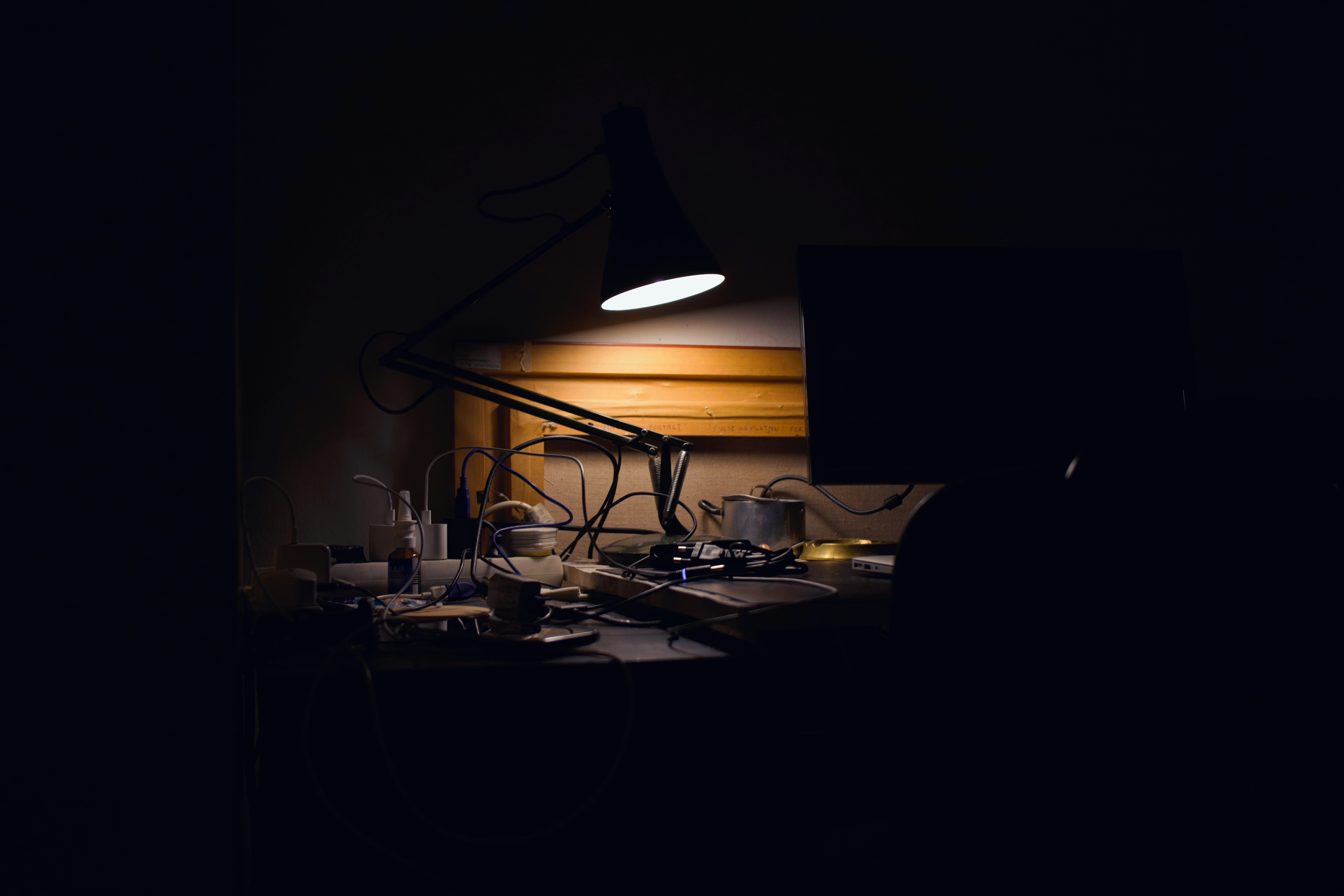 Architect swing-arm desk lamp with articulated joints casting controlled light across a dark wood desk surface