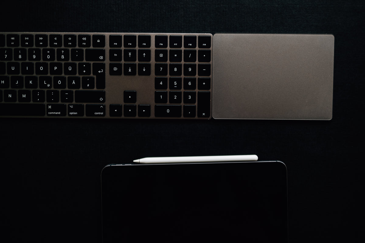 Close-up of a premium leather and felt desk mat with organized workspace accessories including pen, notebook, and keyboard