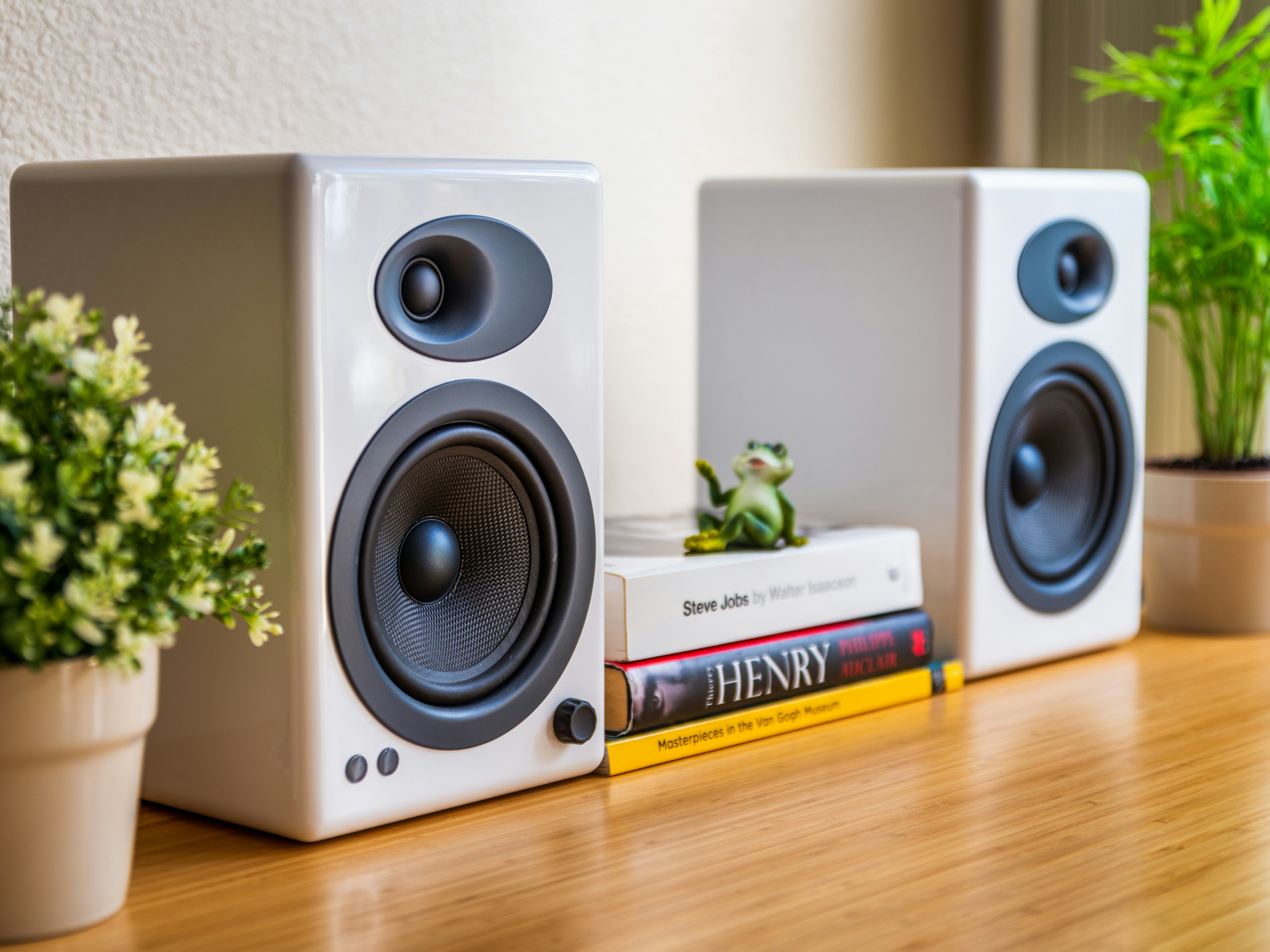 Near-field desktop speakers positioned on either side of a widescreen monitor, angled inward toward the seating position